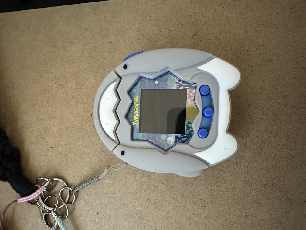 image of blue water tamagotchi paradise in a grey and white shark-themed case